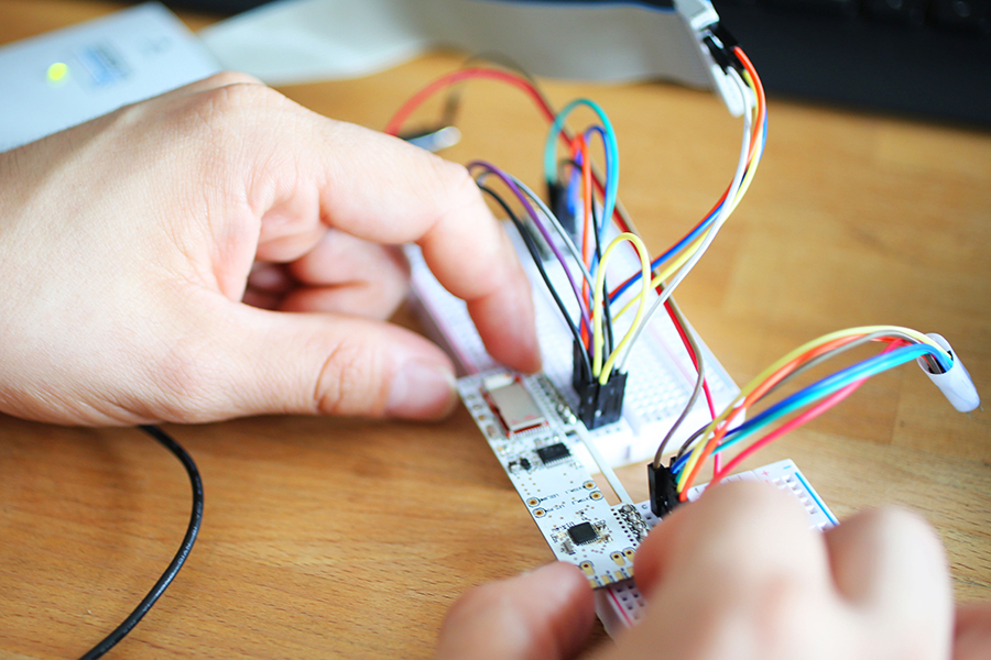 electrical engineer testing a printed circuit board with attached wires.